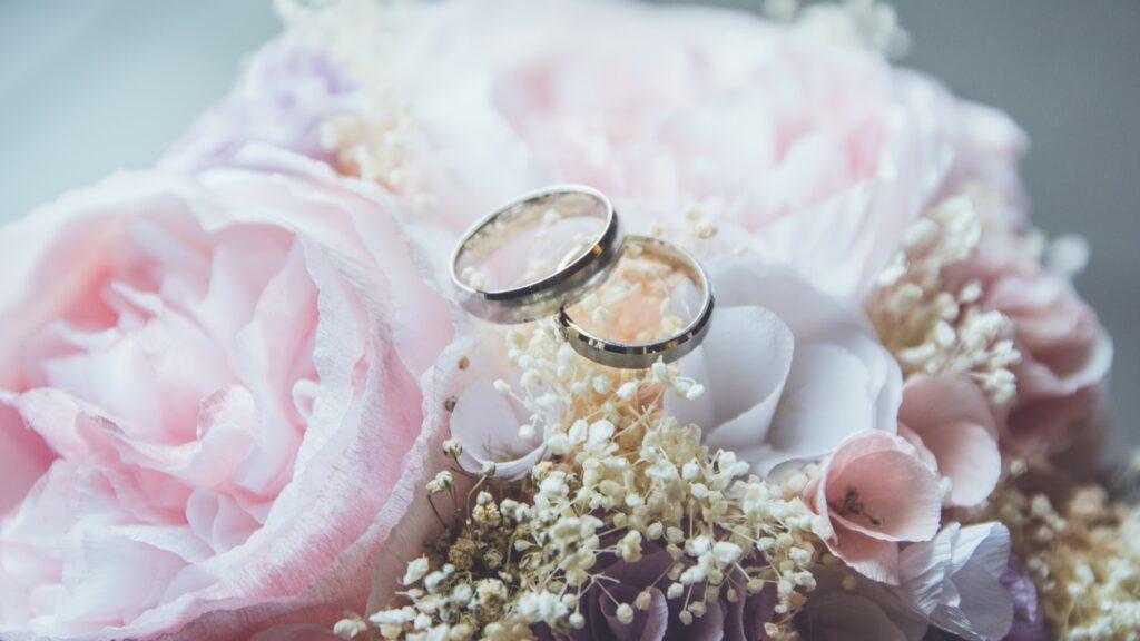 gold-colored bridal ring set on pink rose flower bouquet
